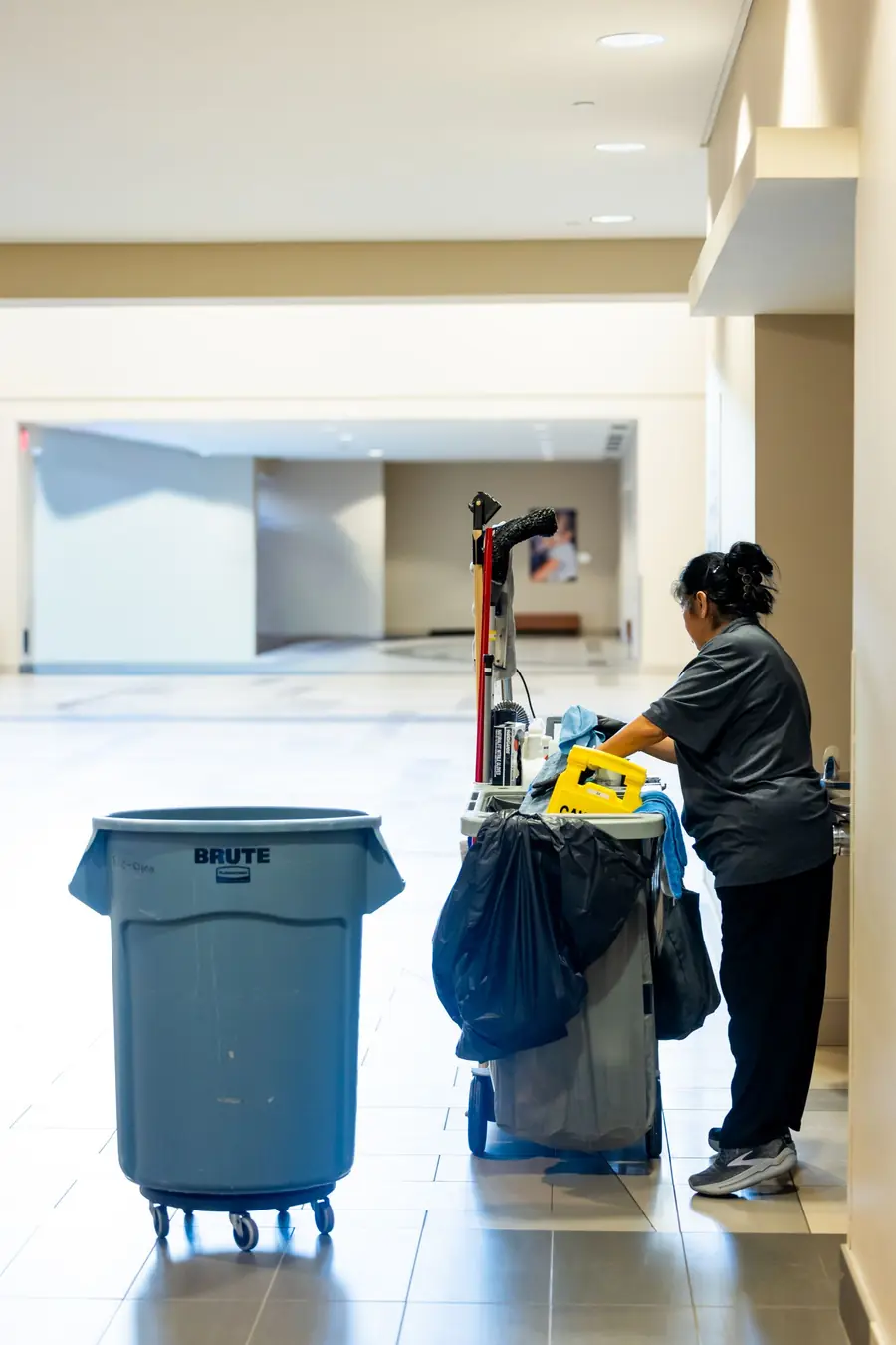 A custodian with a cleaning cart in a hallway