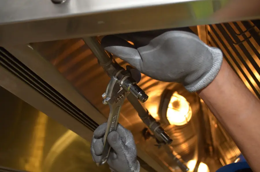 Hands tightening a fitting with a wrench