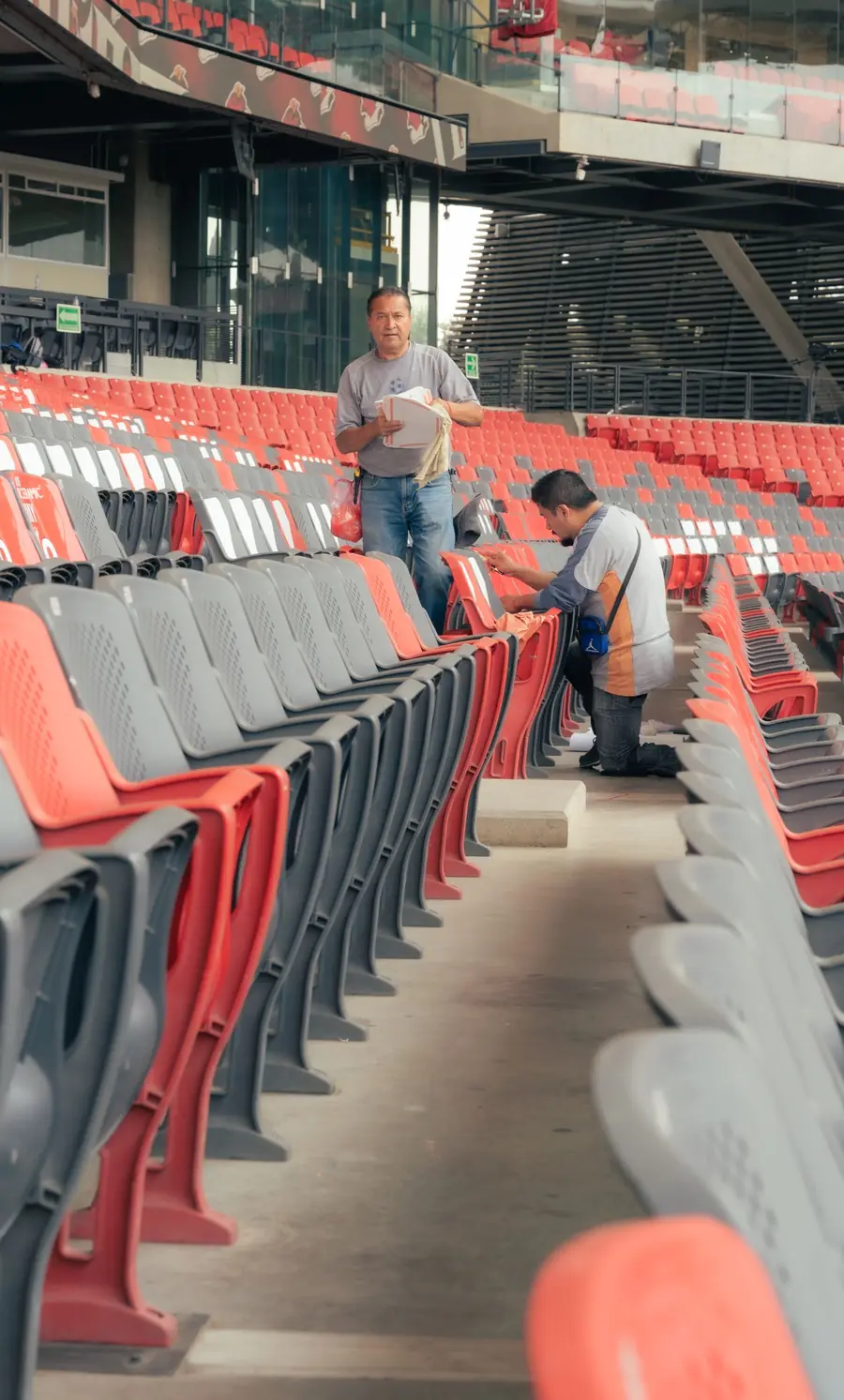 Two workers cleaning rows of stadium seats